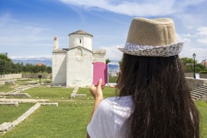 A young girl by cell phone photographed of The smallest cathedral in the world, church of the Holy cross, Nin, Croatia